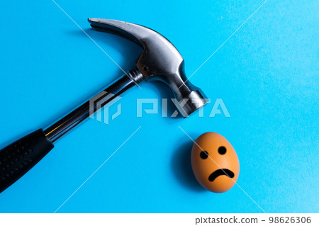 Hammer is hitting on an egg with blue background. minimal idea creative concept. Hammer is hitting on an egg with blue background. minimal idea creative concept. 98626306