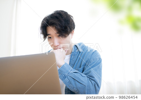 一個男人微笑著看著電腦，前面有綠色模糊 98626454