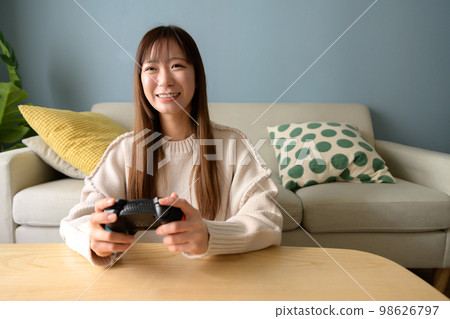 Woman playing games in the living room, game girl, game controller, lifestyle, new normal, natural light 98626797