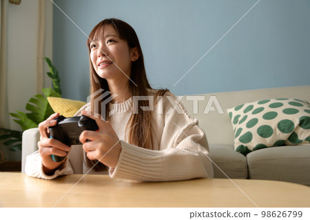 Woman playing games in the living room, game girl, game controller, lifestyle, new normal, natural light 98626799
