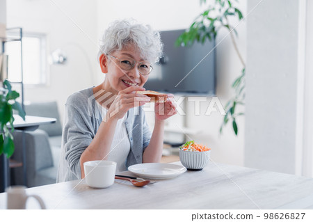 Senior woman eating breakfast with a smile 98626827