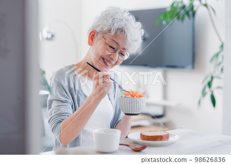 Senior woman eating breakfast with a smile 98626836