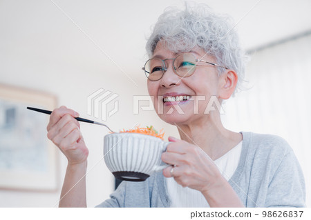 Senior woman eating breakfast with a smile 98626837