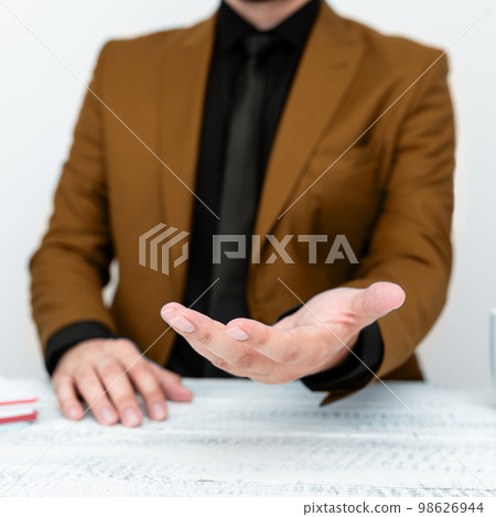 Businessman in Brown jacket Holding Important Message In One Hand. Man In Suit Showing New Crutial Idea In Palm. Executive Presenting Updated Critical Information. Businessman in Brown jacket Holding Important Message In One Hand. Man In Suit Showing New Crutial Idea In Palm. Executive Presenting Updated Critical Information. 98626944