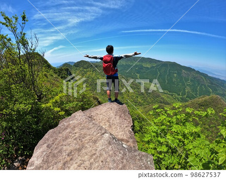 Climber standing on Zazen rock of Mt. Taradake Climber standing on Zazen rock of Mt. Taradake 98627537