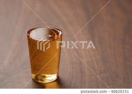 Organic apple cider in tumbler glass on wood table Organic apple cider in tumbler glass on wood table 98628151