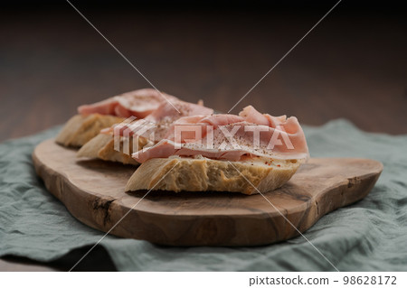 Toassted baguette slices with prosciutto cotto and cream cheese on olive wood board Toassted baguette slices with prosciutto cotto and cream cheese on olive wood board 98628172