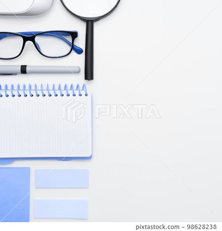 Office Supplies Over Desk With Keyboard And Glasses And Coffee Cup For Working Remotely, Assorted School Utilities For Studying With Hot Drink And Eyeglasses. 98628238