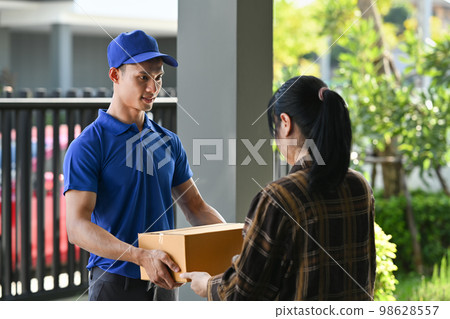 Delivery man giving postal package to customer at doorway. Delivery service, post and shipping concept Delivery man giving postal package to customer at doorway. Delivery service, post and shipping concept 98628557