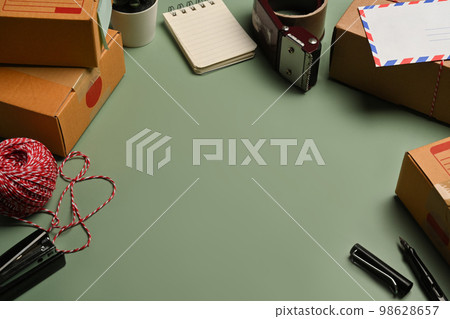 Top view cardboard boxes, tape and clews of rope on green background with copy advertising space. Celebration preparations 98628657