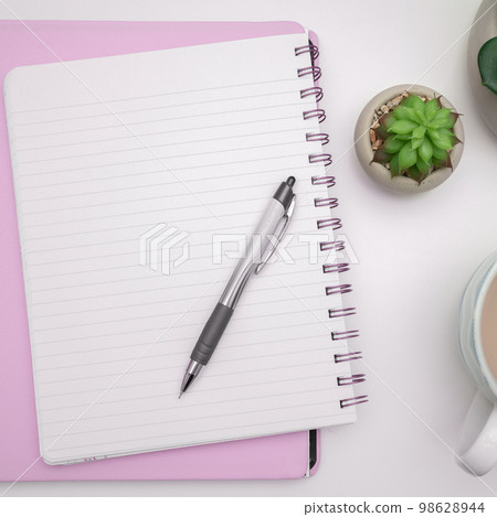 Pot with Plant and Coffee Cup Standing on White Desk. Important infrormation written on paper. Different Office Supplies, Pencils, Pens, Marckers. Computer keyboard. 98628944