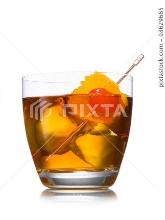 Old fashioned cocktail with ice cubes and cherry with orange peel on white. 98629665