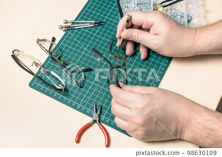 repairman replaces eyeglass nose piece close up 98630109