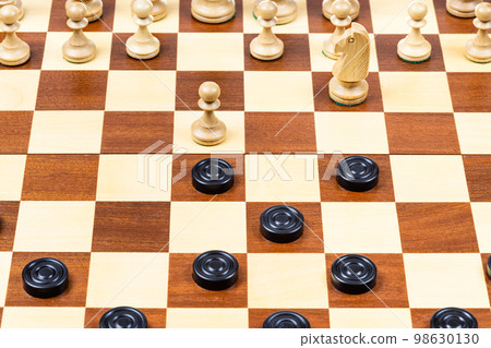 beginning of chess - checkers game on wood board beginning of chess - checkers game on wood board 98630130