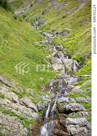 Beautiful waterfall in the mountains. Water flows down from the mountains. 98630224