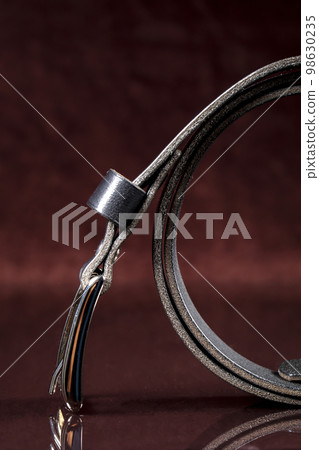 Part of a leather belt on a dark background. 98630235
