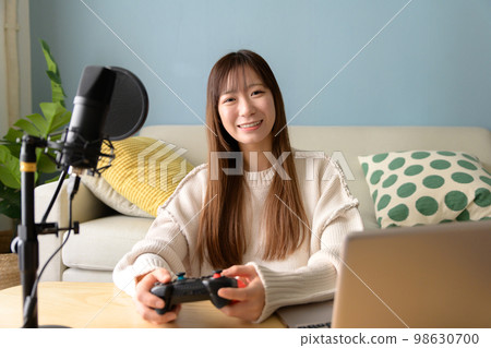 A woman who distributes games with a computer and a microphone, a game girl, a live commentary on a game, a YouTuber 98630700