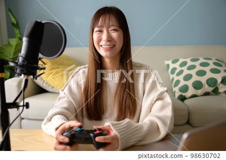A woman who distributes games with a computer and a microphone, a game girl, a live commentary on a game, a YouTuber 98630702