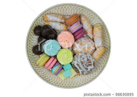 Sweet desserts in plate for the holiday. Marshmallows, macaroons, cake and chocolate candies in a large plate. Top view. 98630895