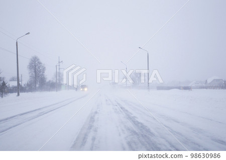 Snow covered foggy road in bad winter weather. 98630986