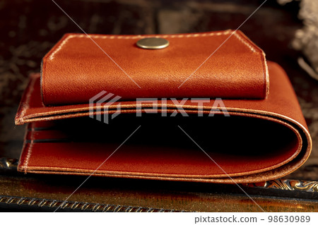 Part of a brown leather wallet or case with stitching. 98630989