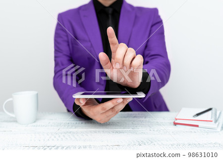 Businessman in Purple jacket sitting at table holding mobile phone And Pointing With One Finger On Important Message. Gentleman Showing Critical Announcement. Businessman in Purple jacket sitting at table holding mobile phone And Pointing With One Finger On Important Message. Gentleman Showing Critical Announcement. 98631010