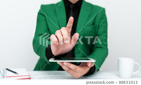 Businessman in Green jacket sitting at table holding mobile phone And Pointing With One Finger On Important Message. Gentleman Showing Critical Announcement. 98631013