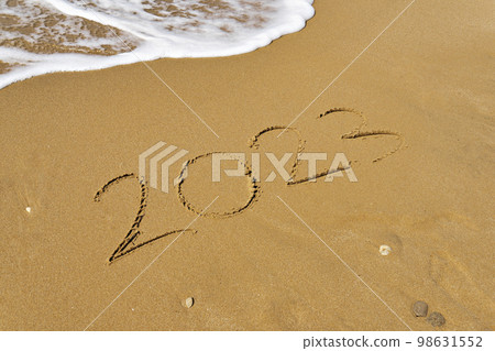 Handwritten Inscription on wet sand 2023 with sea foam and wave. Concept of fresh starts and expectations Handwritten Inscription on wet sand 2023 with sea foam and wave. Concept of fresh starts and expectations 98631552