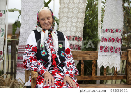 An old Belarusian or Ukrainian woman in an embroidered shirt. Slavic elderly woman in national ethnic clothes. 98631631