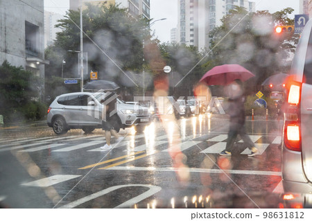 People walking down the street with umbrellas 98631812