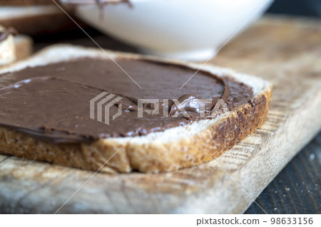 Chocolate butter spread on bread while cooking breakfast Chocolate butter spread on bread while cooking breakfast 98633156