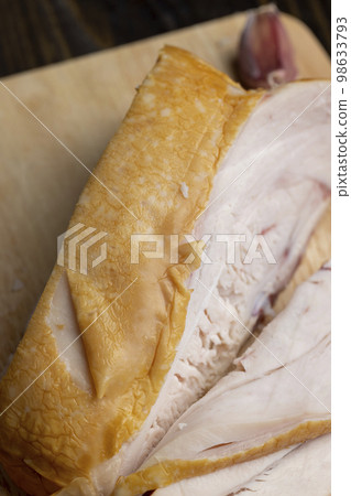 Smoke-smoked chicken is cut up on a board 98633793