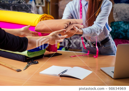 redhead ginger tailor woman give tissue cut to client in textile shop 98634969