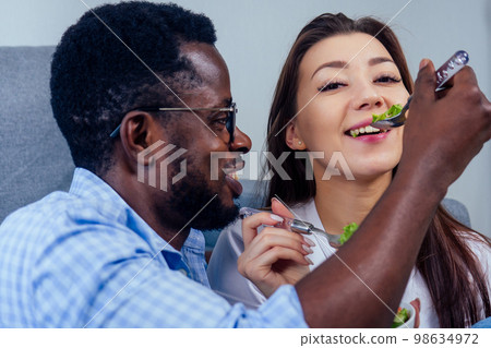 african american man eating salad with woman in living room african american man eating salad with woman in living room 98634972