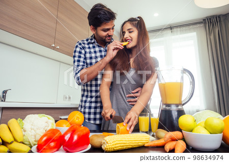 healthy and eco lifestyle.happy indian woman with her husband making smoothie in big kitchen healthy and eco lifestyle.happy indian woman with her husband making smoothie in big kitchen 98634974