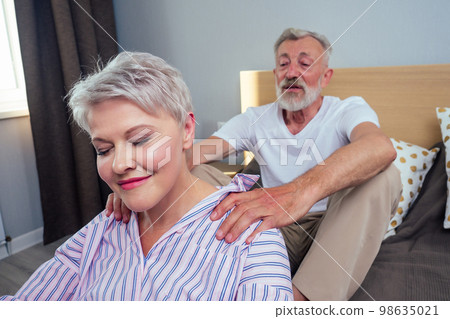 old couple in love in pajamas touching each other in bedroom,mornind day light from big window 98635021