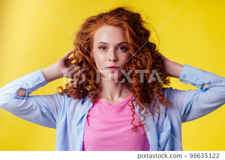 happy young redhaired ginger woman with curly hairstyle pretty face wearing cotton pink shirt in studio yellow background happy young redhaired ginger woman with curly hairstyle pretty face wearing cotton pink shirt in studio yellow background 98635122