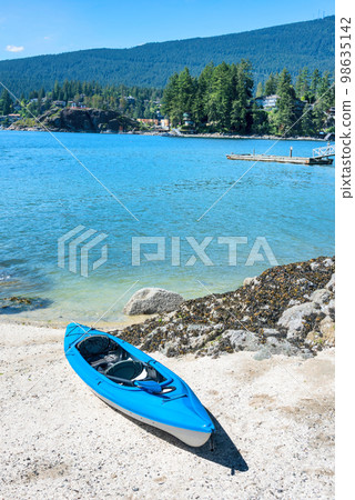 Blue lightweight canoe boat on a shore of Pacific ocean bay on sunny day 98635142