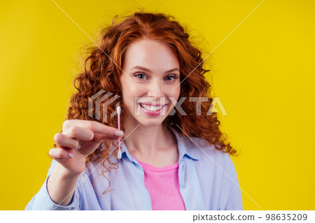 curly redhead caucasian woman use ears sticks in studio yellow background 98635209