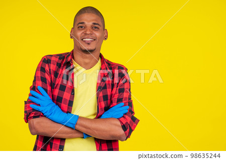 latin brazilian cleaning man wearing ribon gloves in studio yellow background latin brazilian cleaning man wearing ribon gloves in studio yellow background 98635244