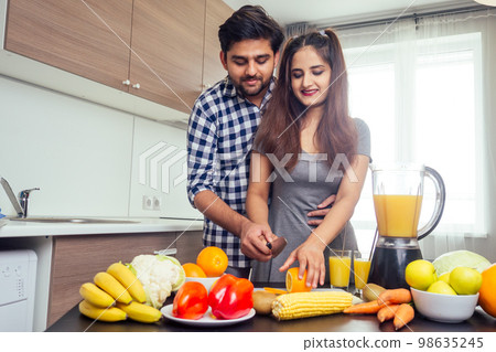 healthy and eco lifestyle.happy indian woman with her husband making smoothie in big kitchen 98635245