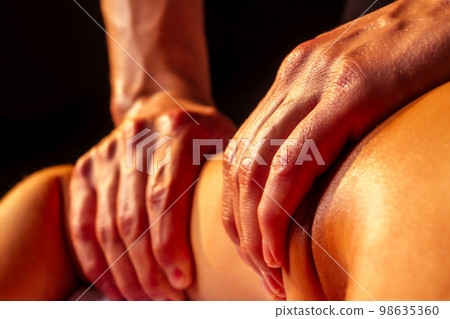 close-up masseur hands doing back massage to female client in spa center 98635360