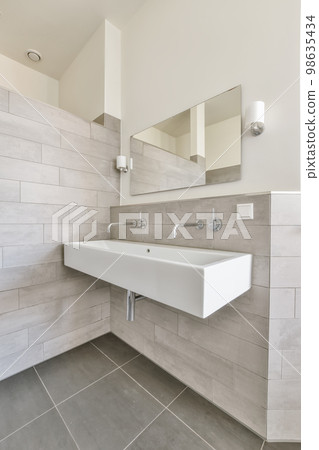 a modern bathroom with grey tiles and white fixtures on the wall above the sink is a large mirror in the corner a modern bathroom with grey tiles and white fixtures on the wall above the sink is a large mirror in the corner 98635434