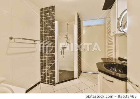 a bathroom with black and white tiles on the walls, shower stall and toilet in the photo is taken to the other side a bathroom with black and white tiles on the walls, shower stall and toilet in the photo is taken to the other side 98635463