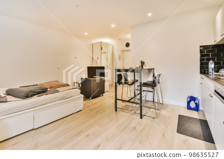 a living room with wood flooring and white walls, there is a small dining table in front of the couch 98635527