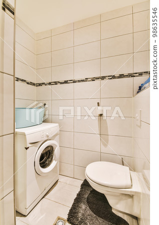a small bathroom with a toilet and washer in the corner, while it is white tile on the walls a small bathroom with a toilet and washer in the corner, while it is white tile on the walls 98635546