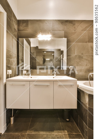 a modern bathroom with black and white tiles on the walls, sink, mirror and shower stall in the corner a modern bathroom with black and white tiles on the walls, sink, mirror and shower stall in the corner 98635562