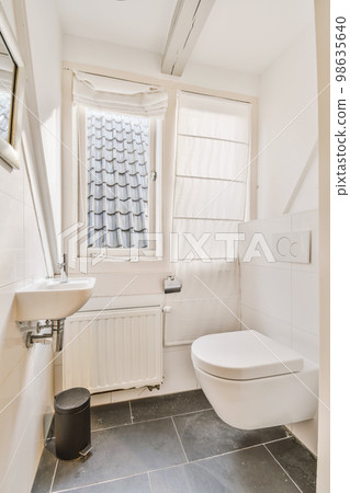 a bathroom with a toilet, sink and window in the corner next to it is a black trash can on the floor a bathroom with a toilet, sink and window in the corner next to it is a black trash can on the floor 98635640
