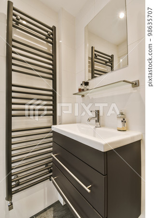 a modern bathroom with black and white tiles on the floor, sink, mirror and towel rack in the corner a modern bathroom with black and white tiles on the floor, sink, mirror and towel rack in the corner 98635707