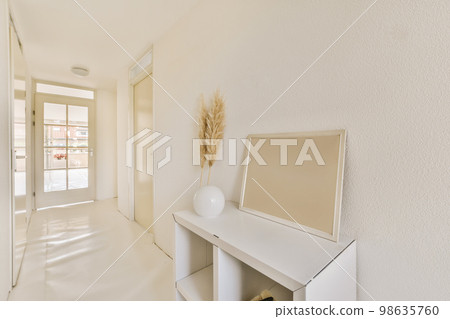 a white room with a mirror on the wall and an open door to another room in the photo is taken a white room with a mirror on the wall and an open door to another room in the photo is taken 98635760